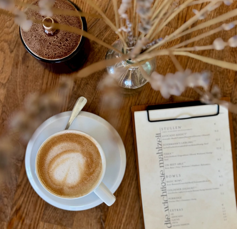 Cappuccino mit Latte Art neben der Fjaka-Speisekarte